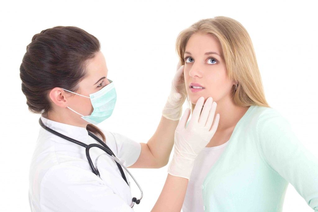 Врач-дерматолог осматривает лицо у пациенткиг